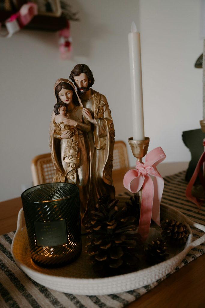 Religious figurines and candle on decorative tray